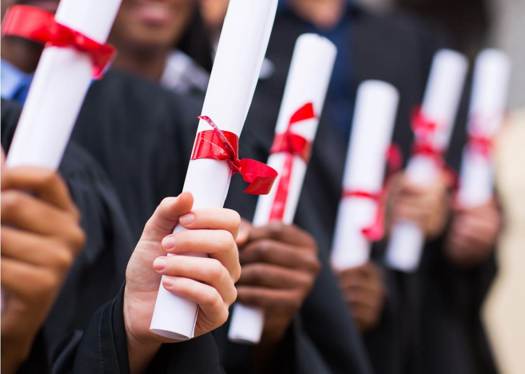 Group of graduates holding diplomas.
