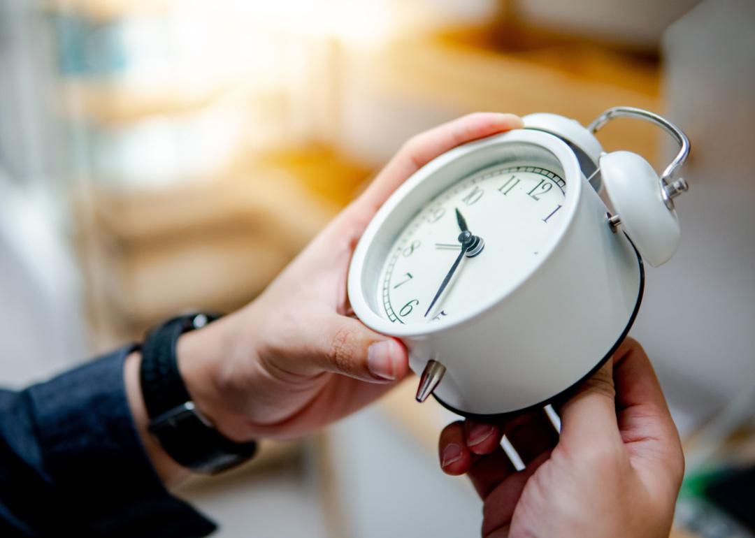 Hand changing the time on alarm clock.