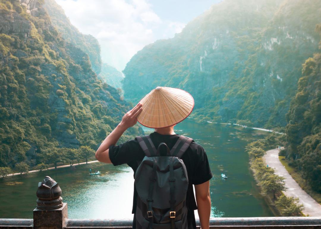 Man wearing hat with backpack sightseeing in Ninh Binh, Vietnam.