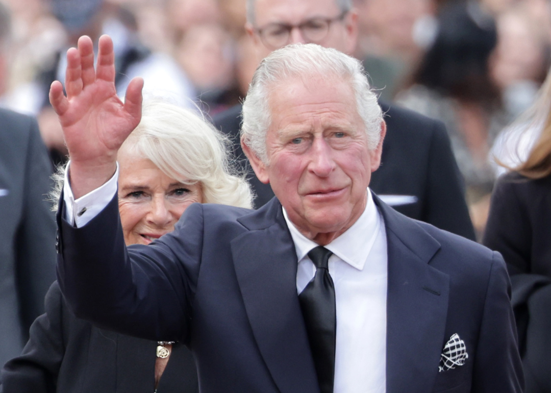 King Charles III waves outside Buckingham Palace.