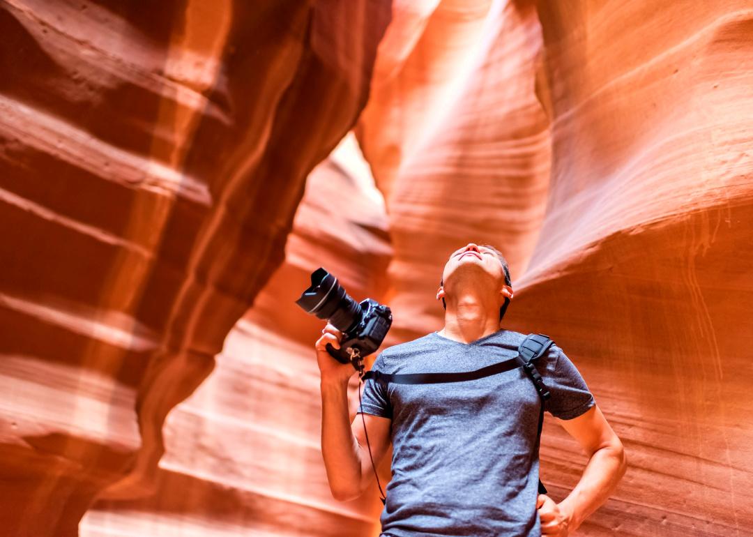 Photographer standing in Antelope canyon holding camera looking up.