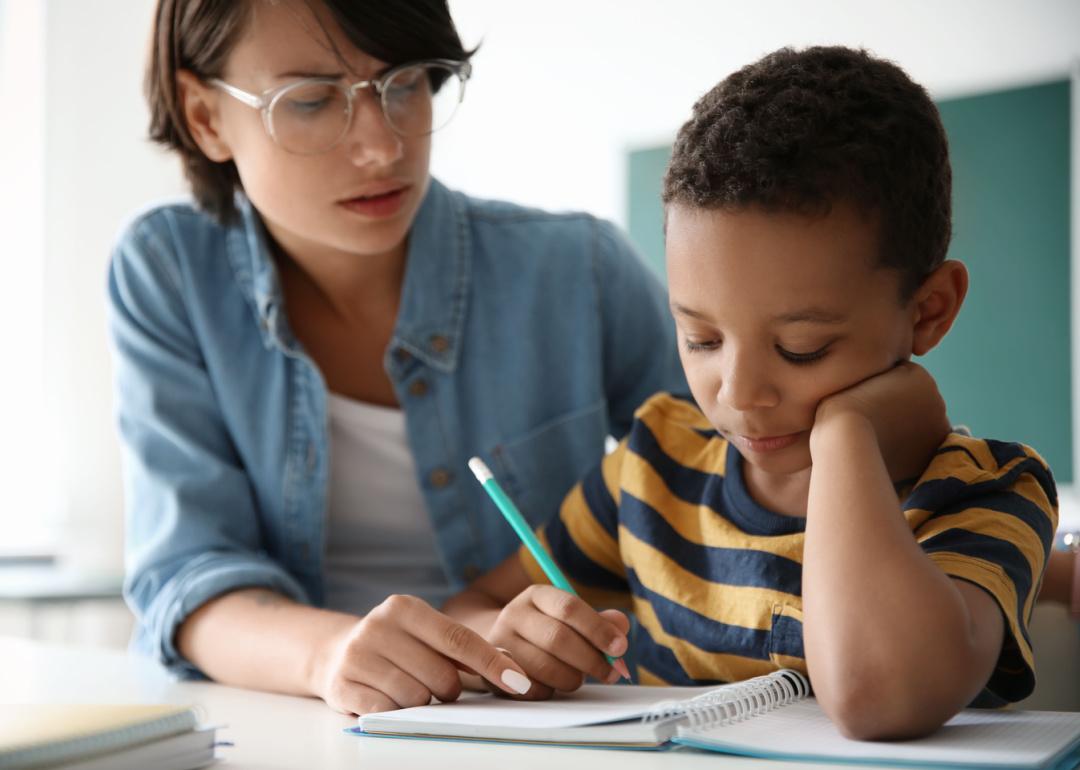 Teacher helping child with assignment.