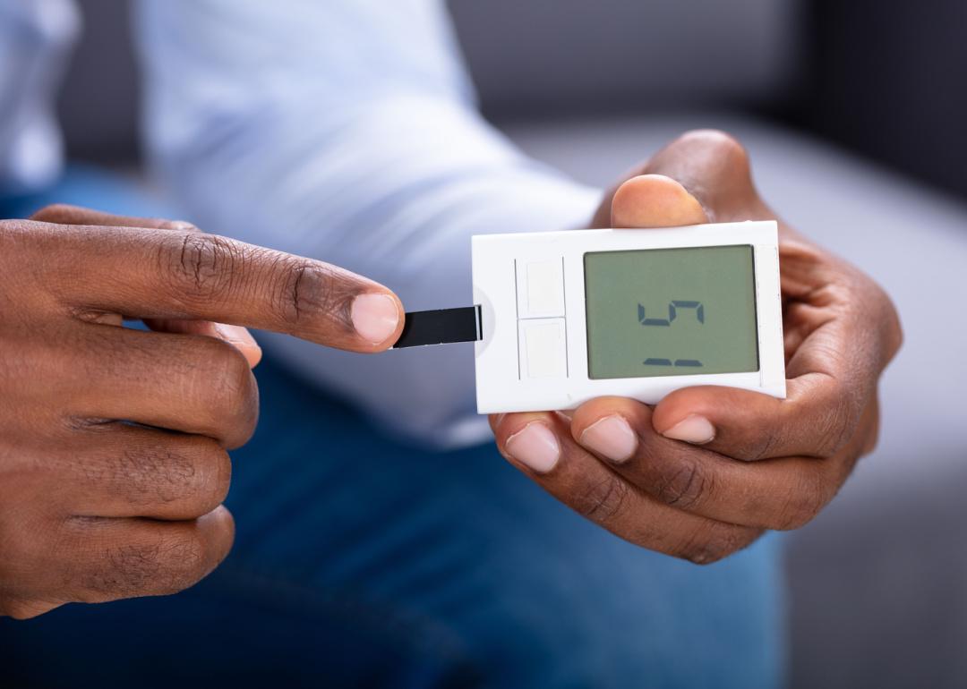 Person checking blood sugar level with glucometer.