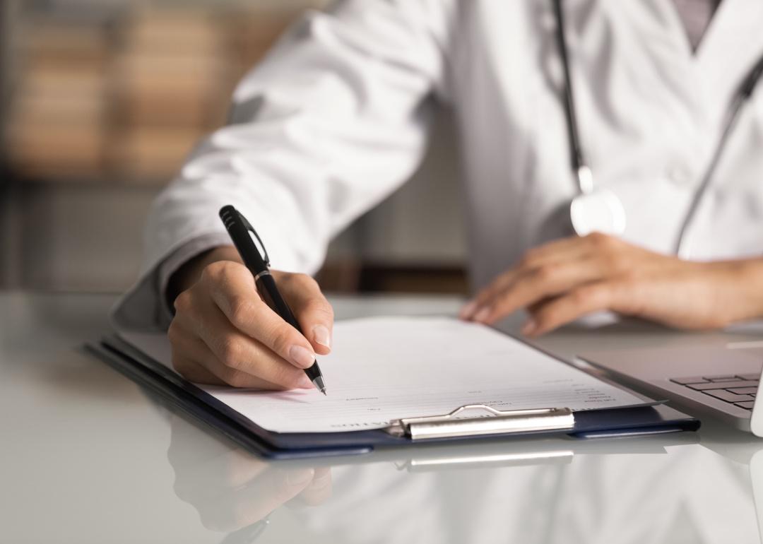 Doctor filling out paper medical records.