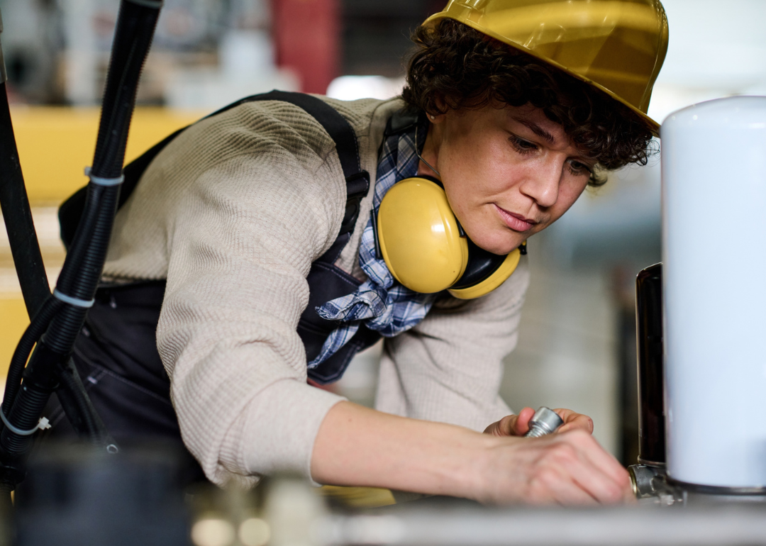 Worker in protective gear assembling industrial equipment