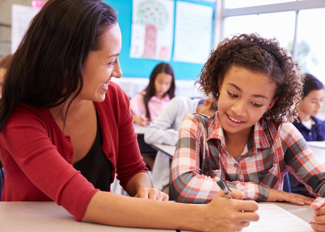 Teacher working with student at her desk.