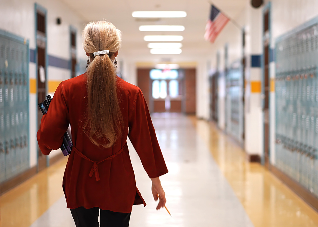 Rear view of teacher walking down school hallway.