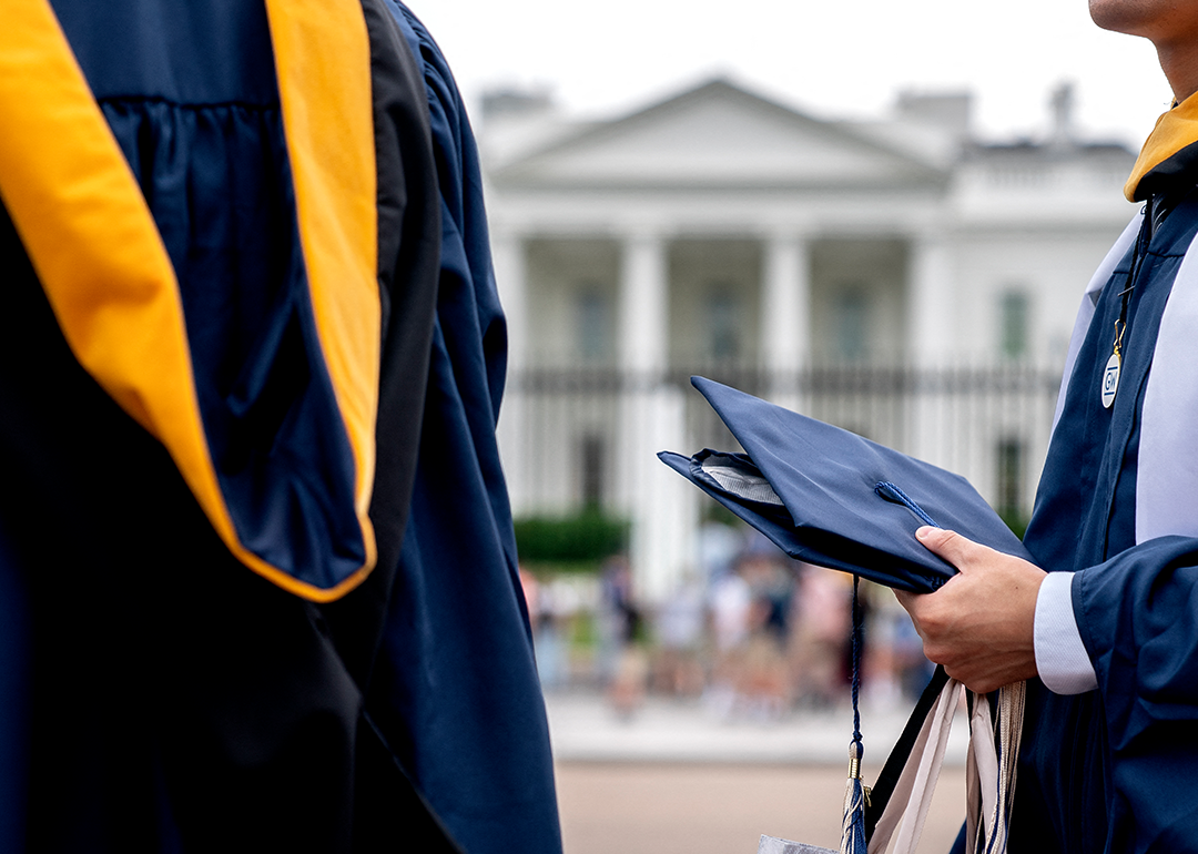 Students wear graduation gowns outside of the White House.