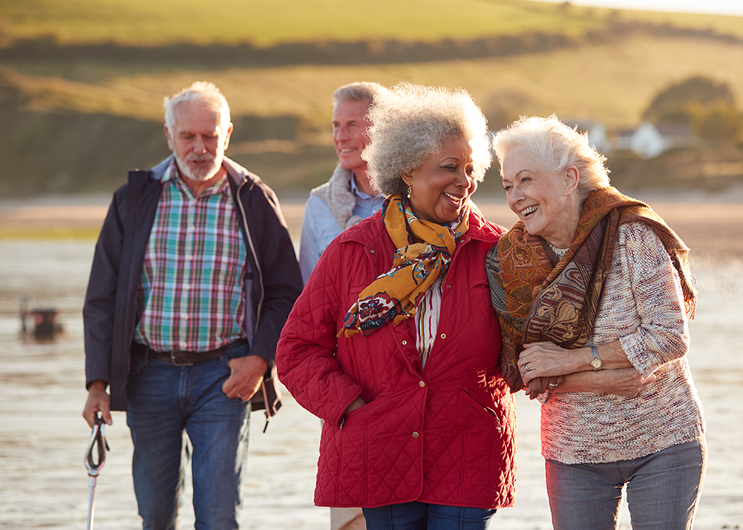 Group of smiling senior friends walking near water.