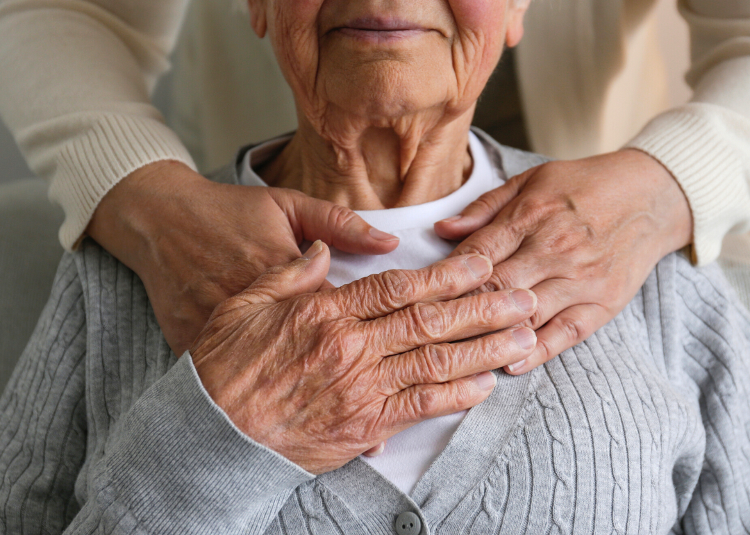 Caring hands holding aging family member.