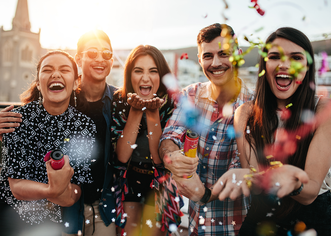 Group of friends throwing confetti on rooftop party.