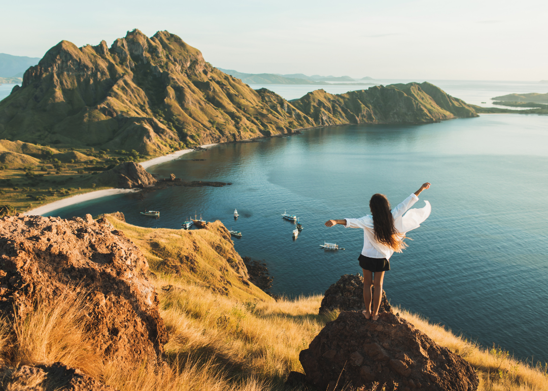 Woman standing on Padar island lookout with arms raised