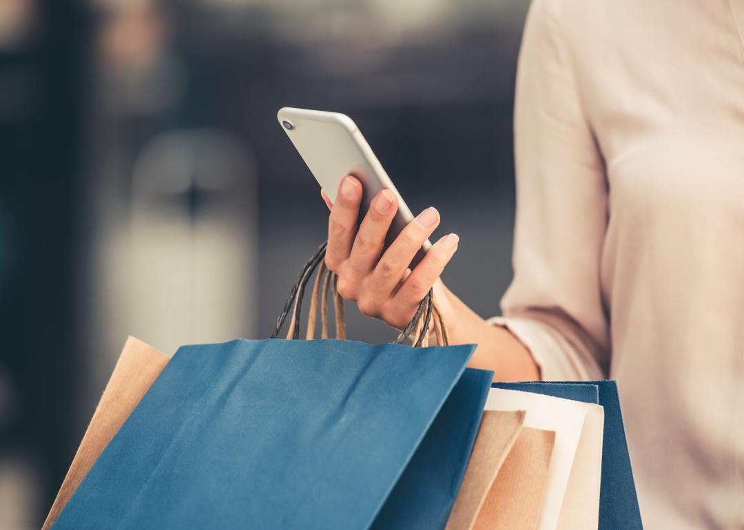 Cropped image of woman holding shopping bags and phone