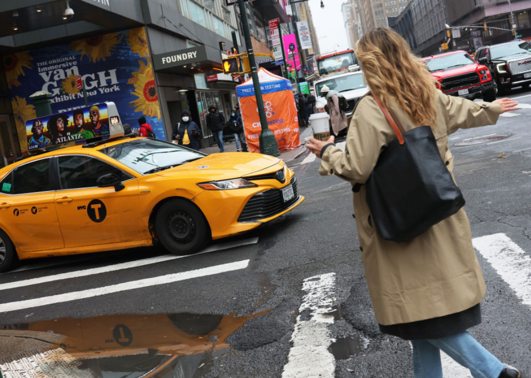 A woman in New York City hails a yellow taxi cab