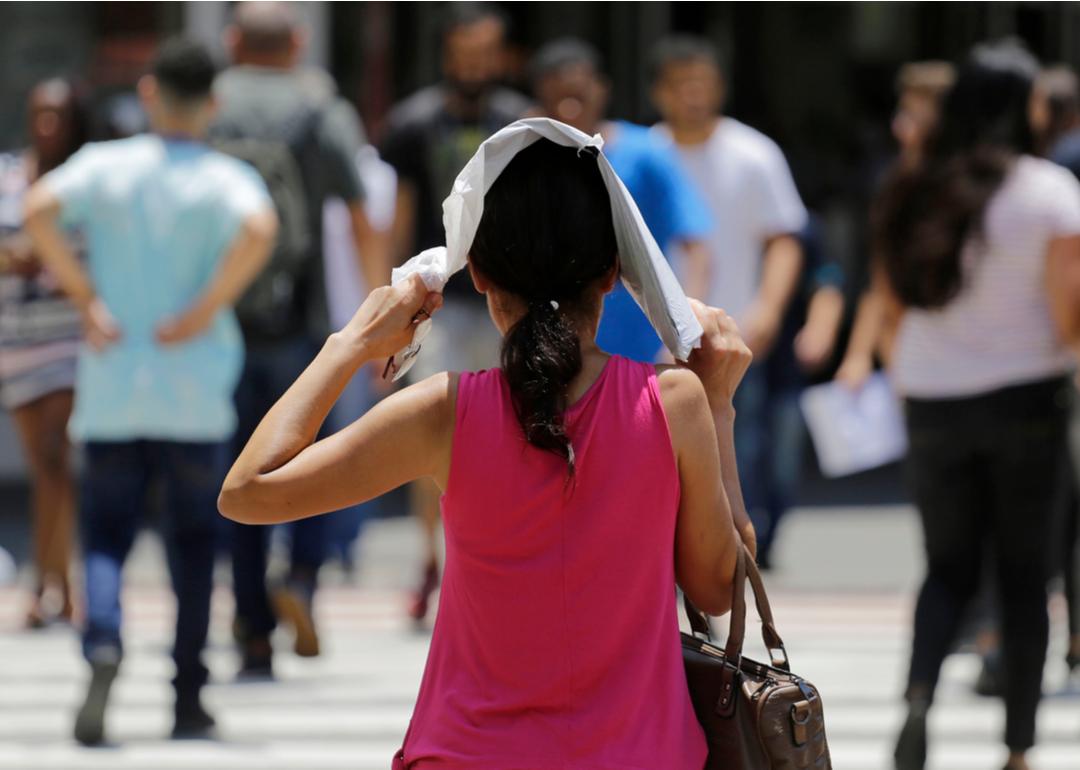 Woman protects herself from the hot sun while she walks down the street during a extreme heatwave