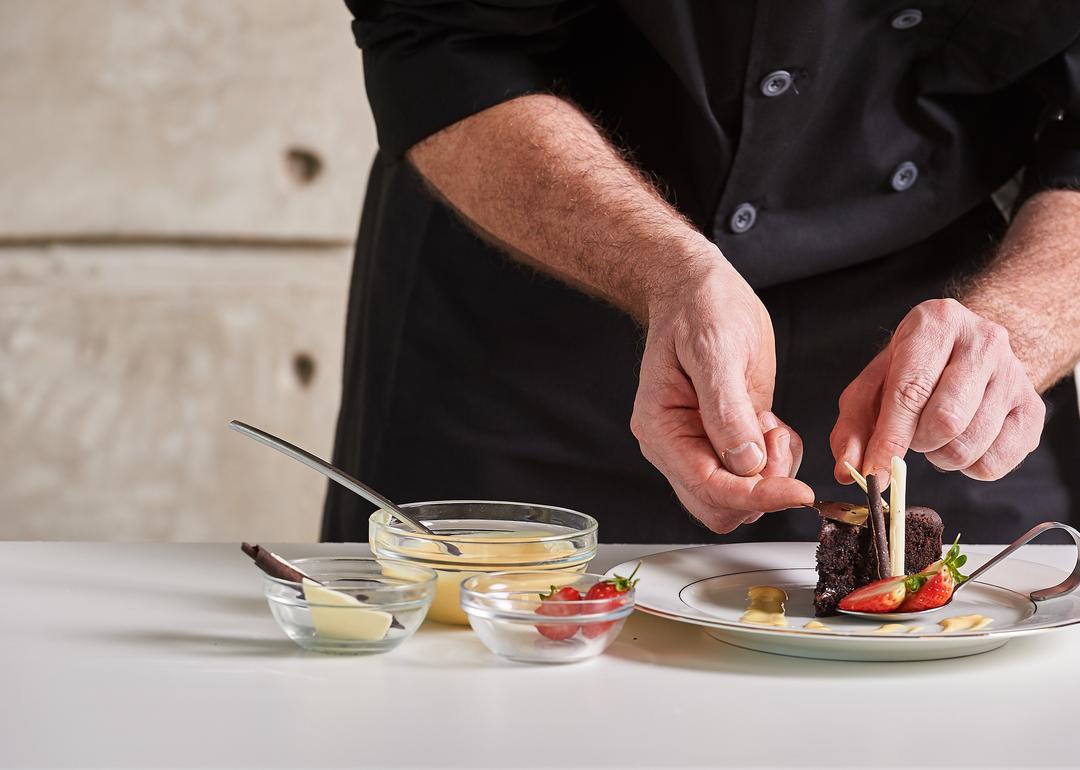 Closeup of private chef in black chef's coat assembling dessert.