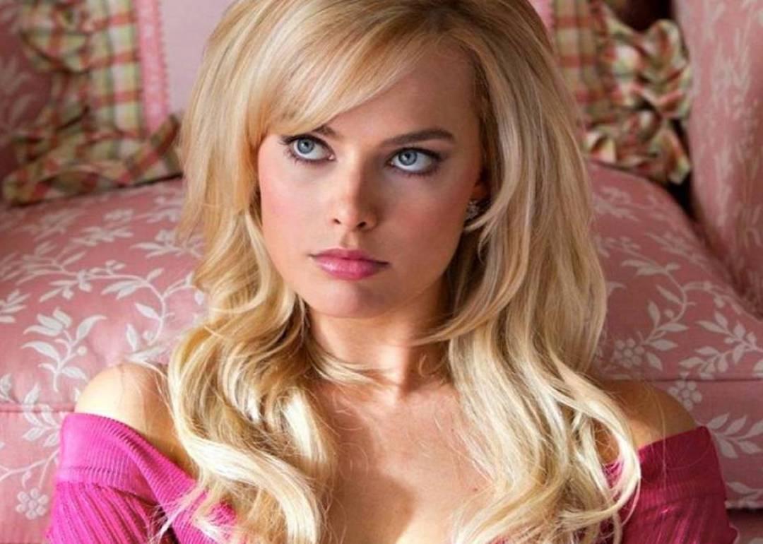 Margot Robbie in a hot pink sweater leaning against a pink chair as Naomi Lapaglia in "Wolf of Wall Street." 
