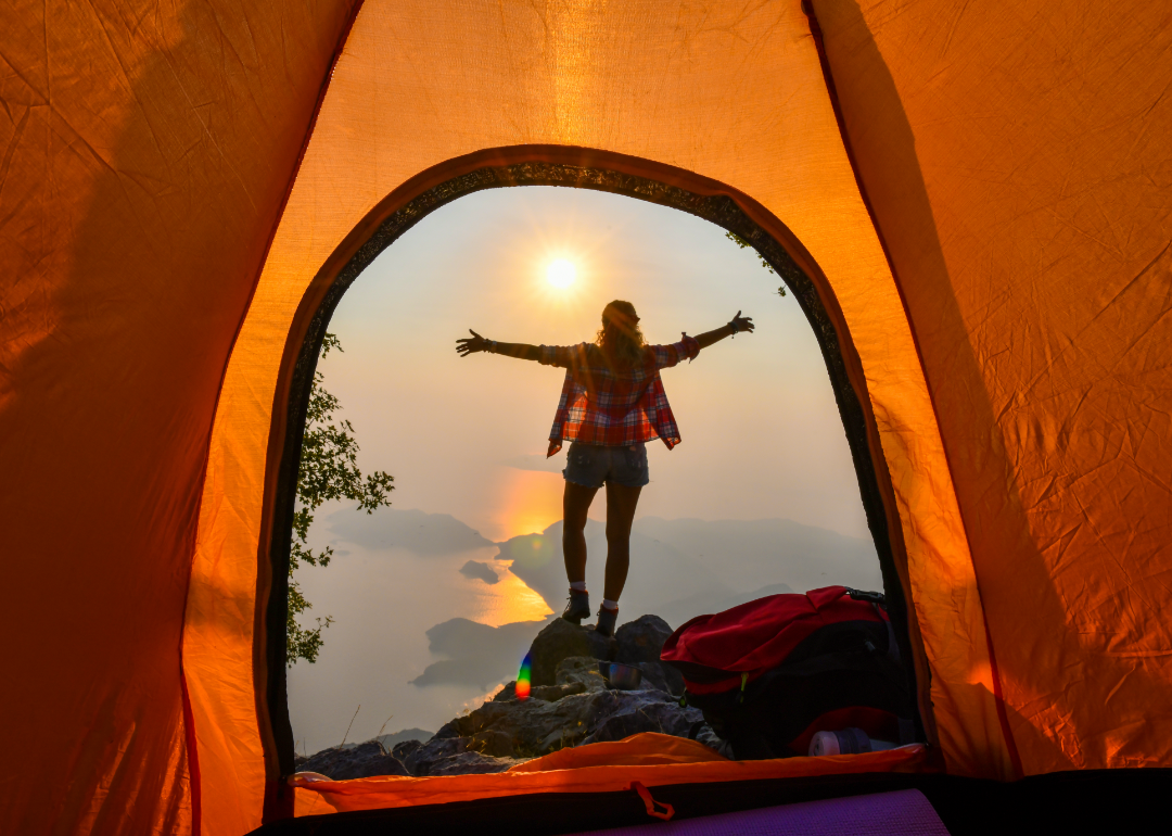 View from inside orange tent of woman camping and looking out at the mountains.