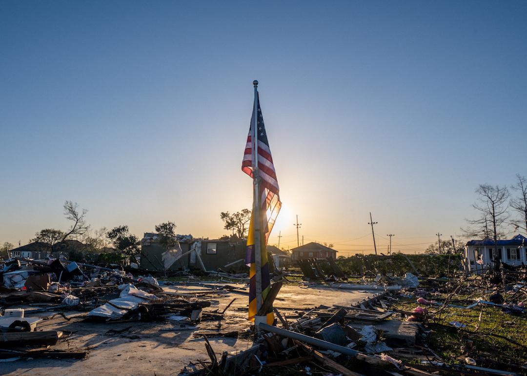 The American and City of New Orleans Mardi Gras flag is seen standing in a field of tornado-damaged wreckage in the Arabi neighborhood on March 24, 2022 in New Orleans, Louisiana.