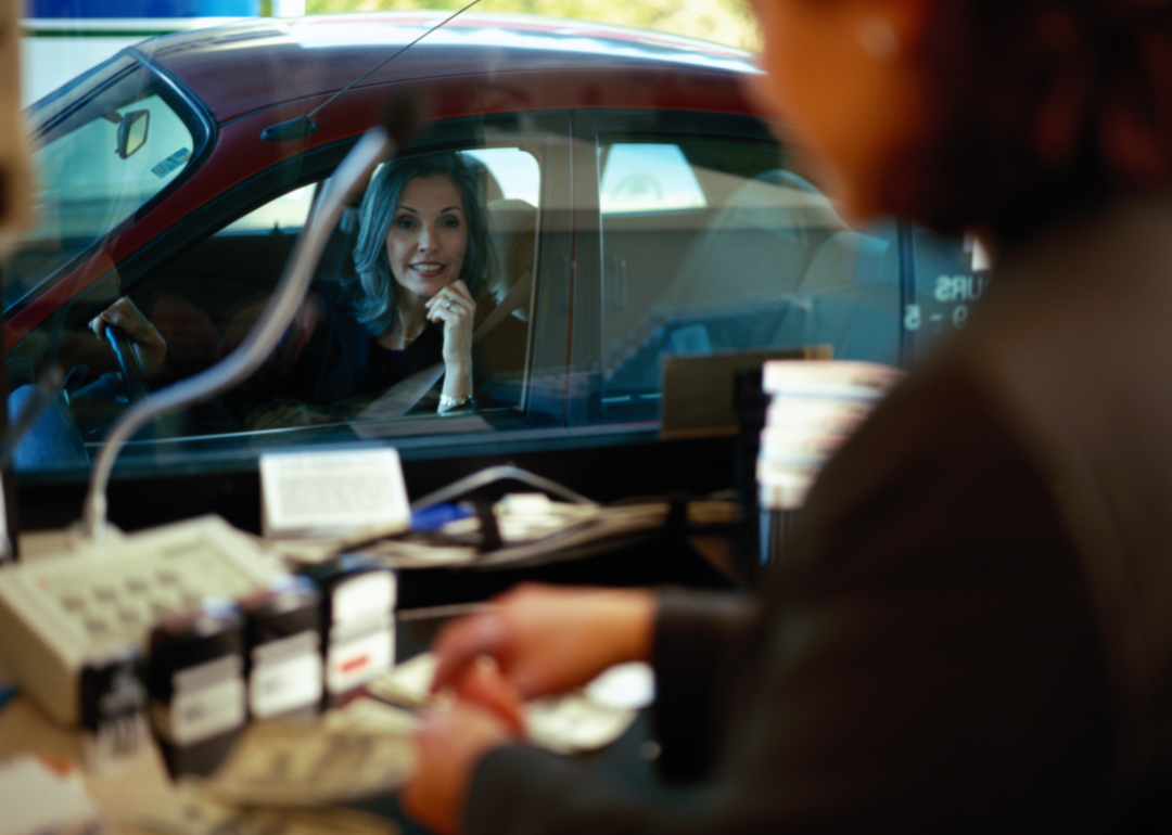 Woman looking through window at drive-through bank teller.