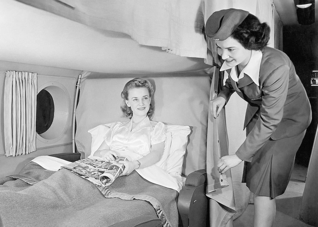 Flight attendant with a reclining passenger on a vintage Boeing Stratocruiser airplane.