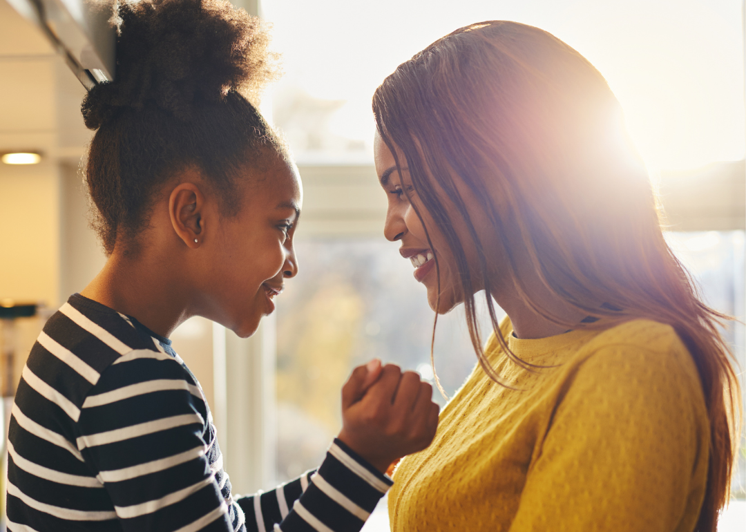 Mom and daughter looking at each other and smiling at home.