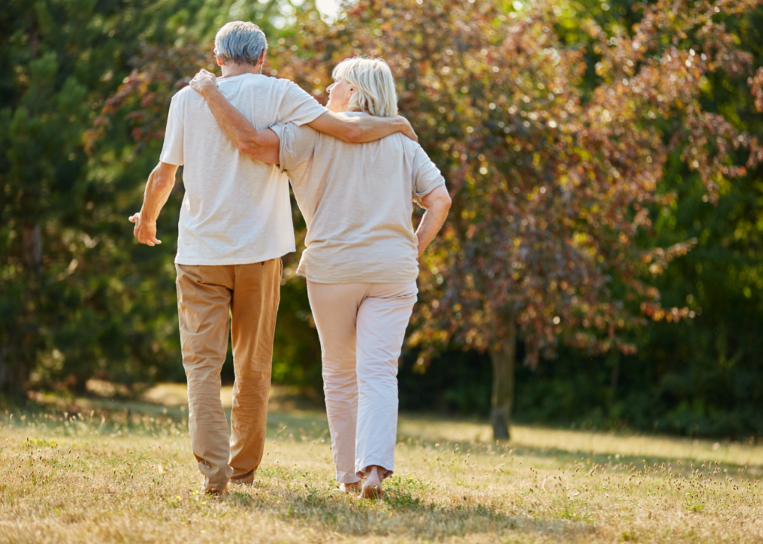Retired couple photographed from behind walking in the park during the fall.