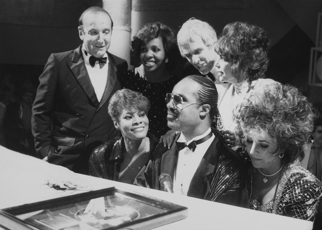 Dionne Warwick, Stevie Wonder, Elizabeth Taylor, Gladys Knight, Burt Bacharach and Carole Bayer Sager at a performance of the song "That's What Friends Are For" in 1986. 
