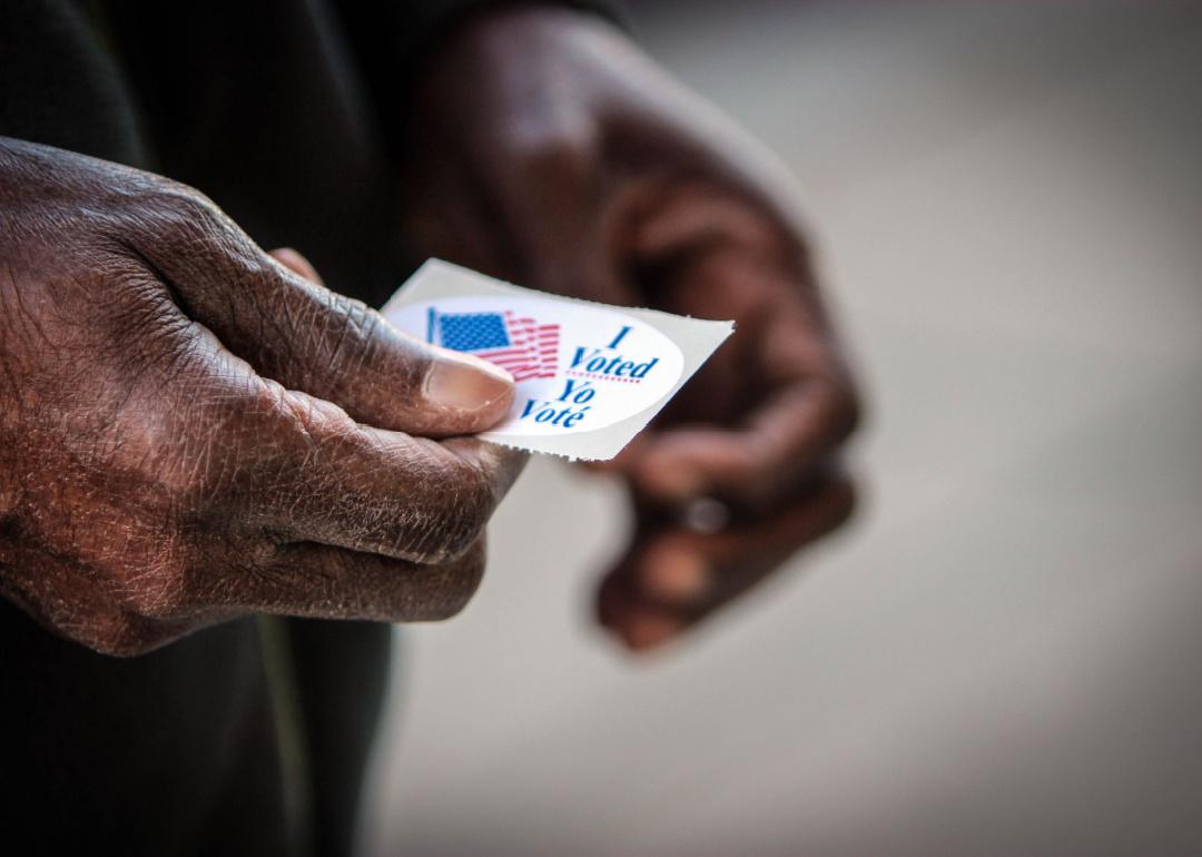 An elderly Black man holds his “I voted” sticker after he cast his ballot in Washington, D.C.
