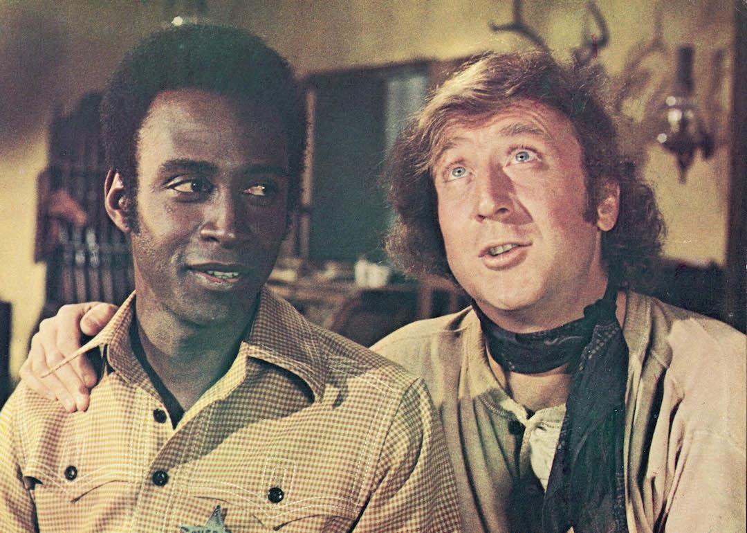 Actor Gene Wilder (right) puts his arm around the shoulder of actor Cleavon Little in a still from the 1974 comedy "Blazing Saddles," directed by Mel Brooks.