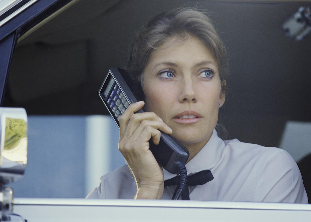 Woman talking on large car phone in the 1980s.