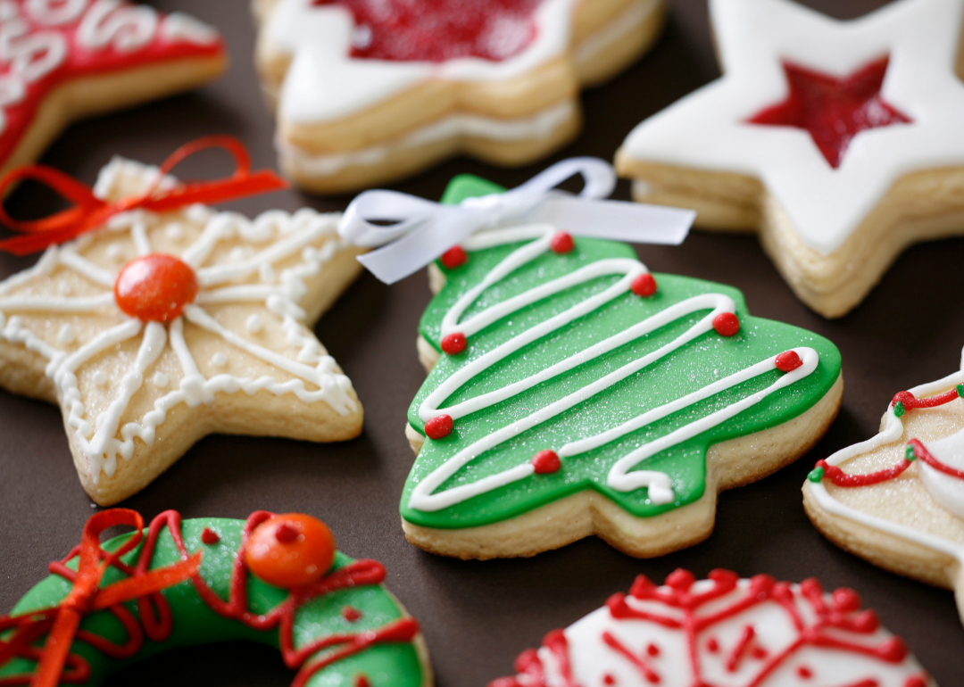 Cookies in the shapes of stars, wreaths, and Christmas trees on a black background.