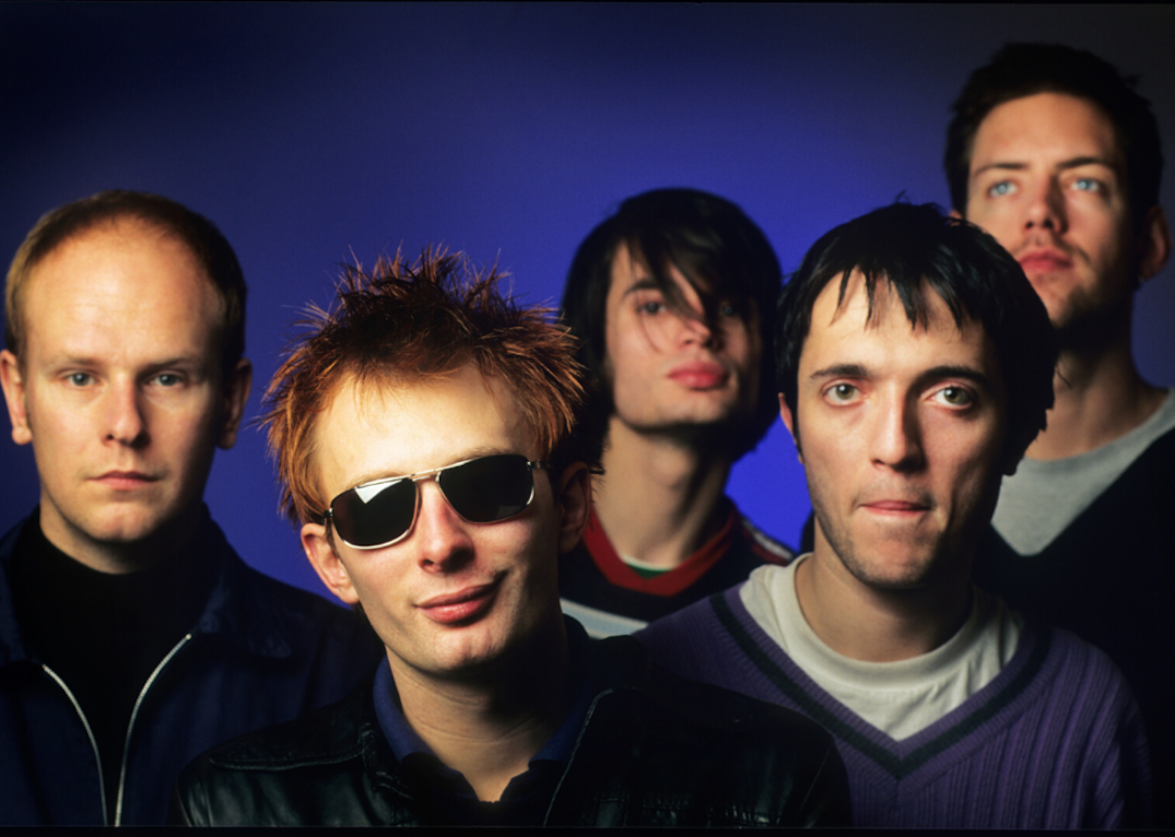 The members of Radiohead—Phil Selway, Jonny Greenwood, Thom Yorke, Colin Greenwood, and Ed O'Brien—stand against a blue background.