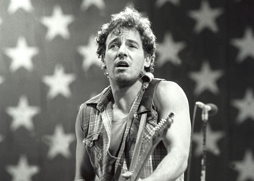 Bruce Springsteen performs in Los Angeles, California with an American flag behind him.