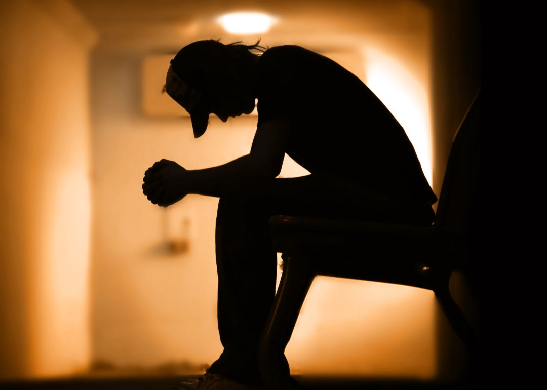 A silhouette of a teenage boy with head hanging low.