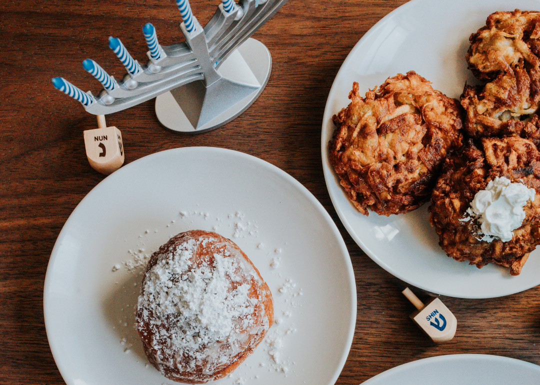 Sufganiyot, latkes, menorah, and dreidels on a table in honor of Hanukkah.