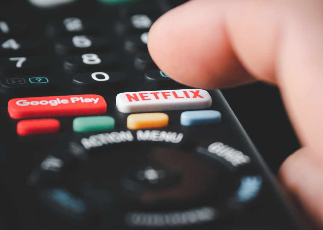 Closeup of a person's finger about to press Netflix on their remote.