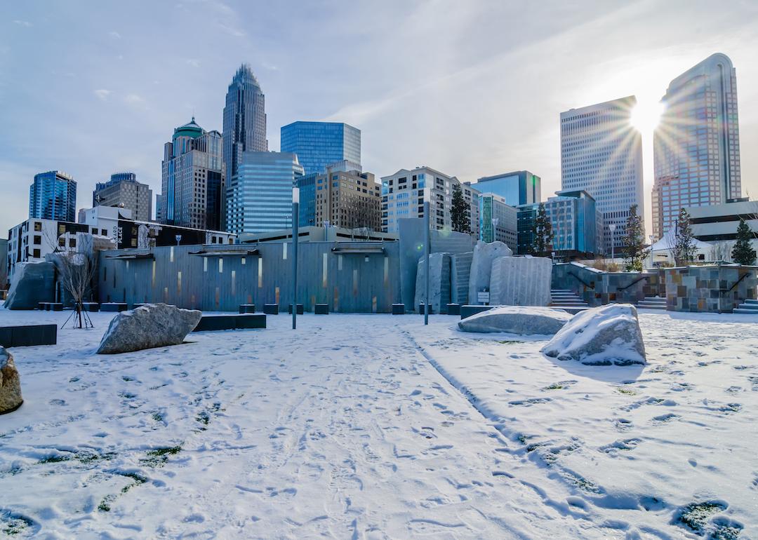 The sun shines on the skyline of Charlotte, North Carolina while covered in snow.