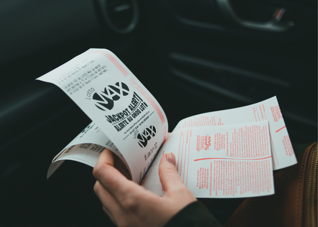 Hand holding a winning lottery ticket in a car.