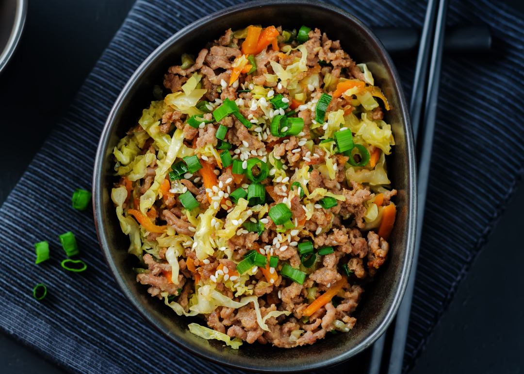 Steak and cabbage stir fry in a black bowl.