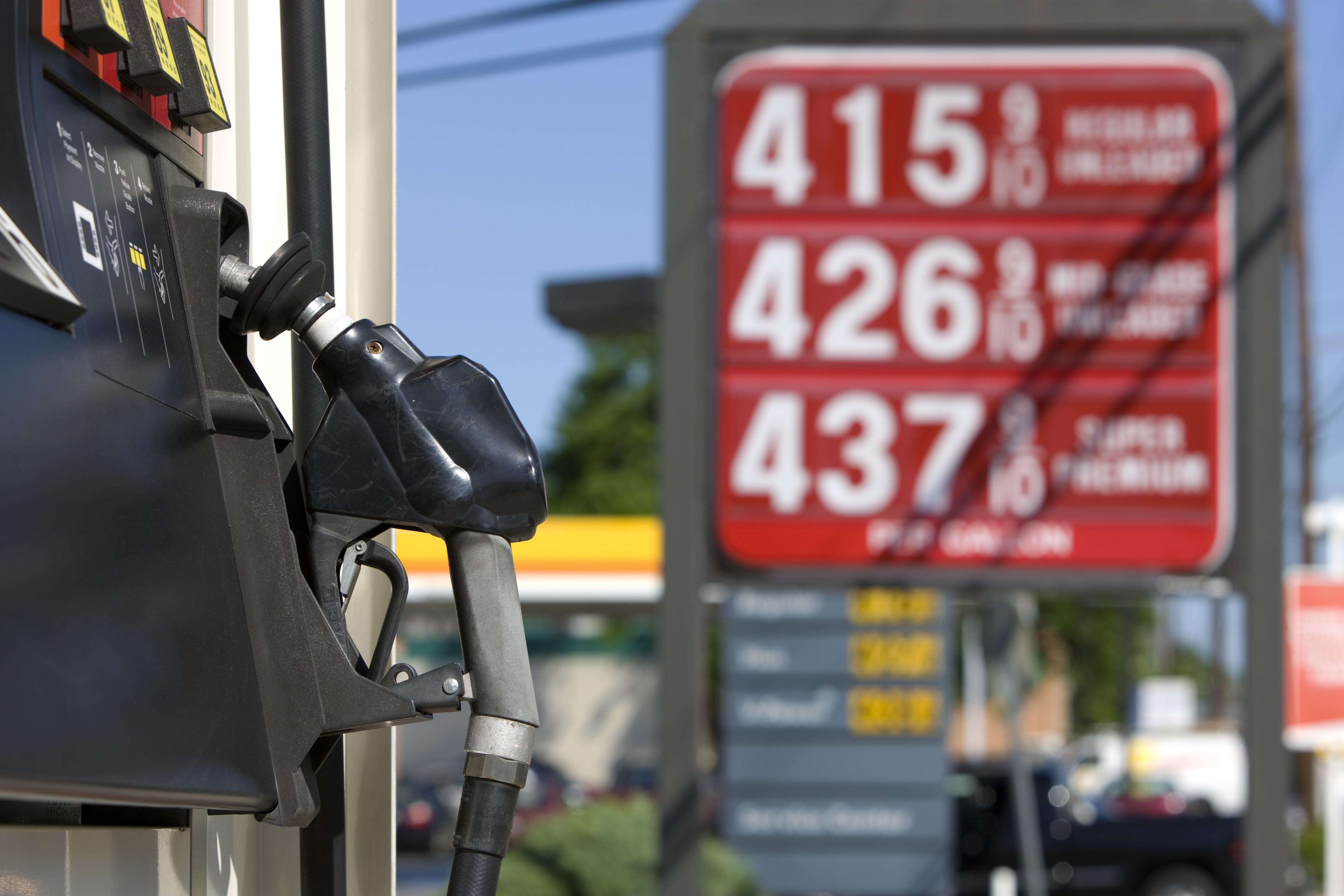 Image of a gas pump in the foreground and a gas price sign in the background