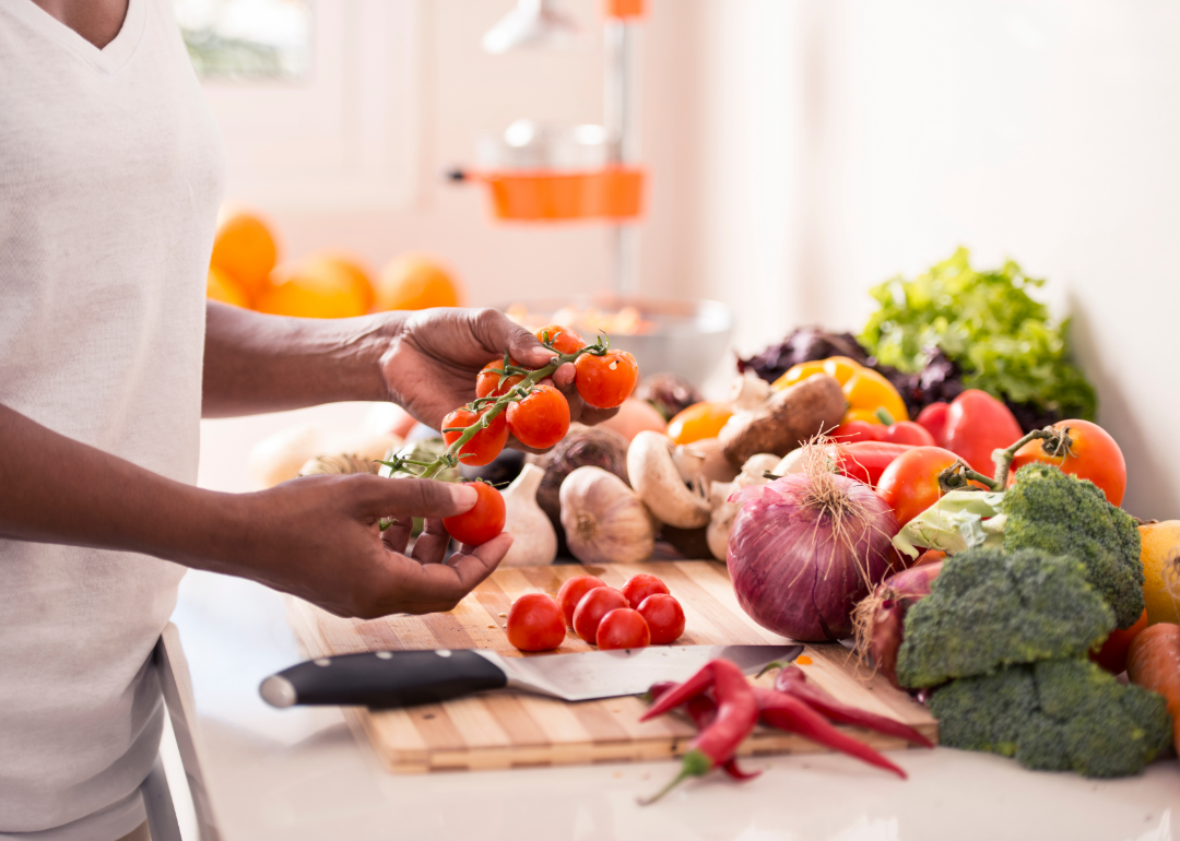 A person inspecting a bunch of vegetables on their kitchen counter.