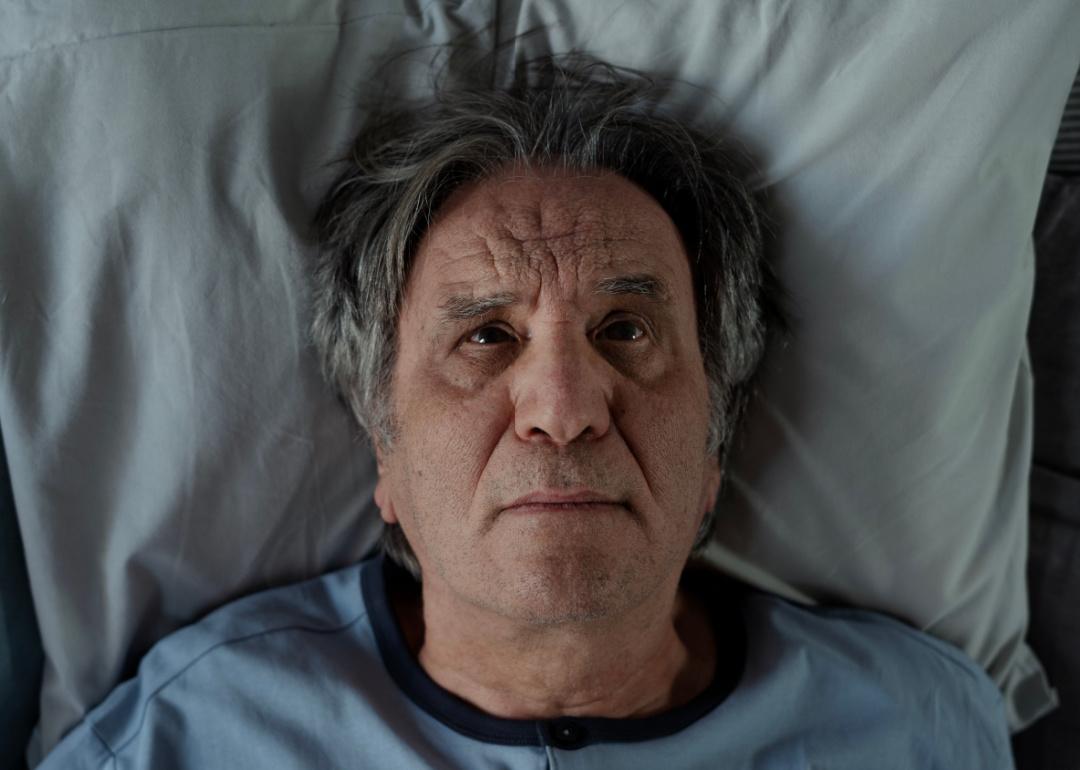 An elderly person in bed woken up from a hypnic jerk.