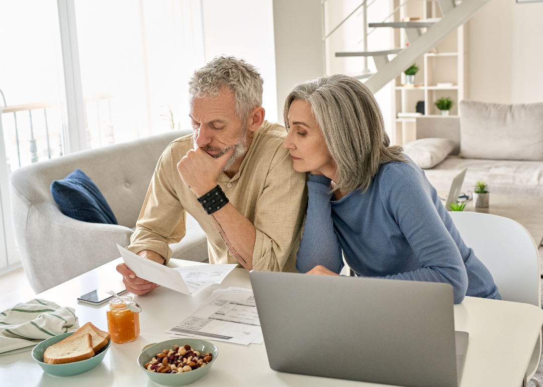 Retired couple checking bills at home over breakfast.