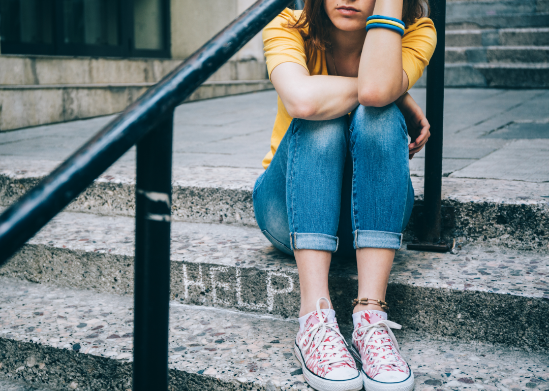 A teenage girl sits alone on a stone staircase.