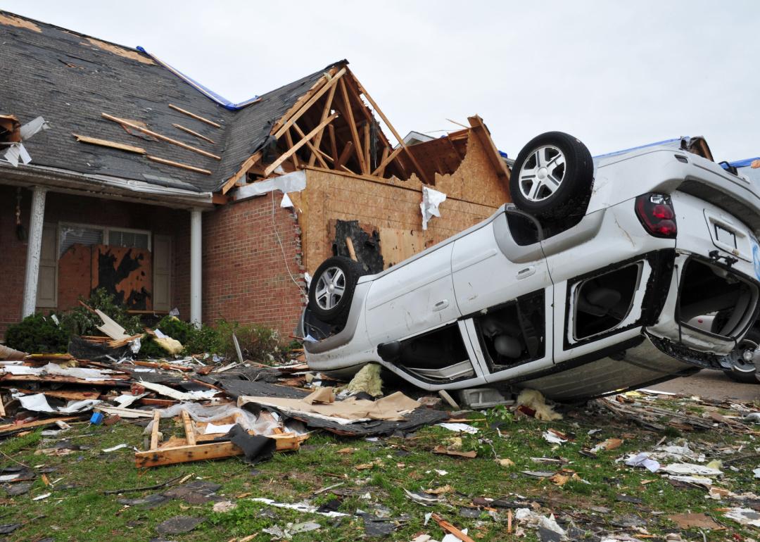 Car and home heavily damaged by a tornado.