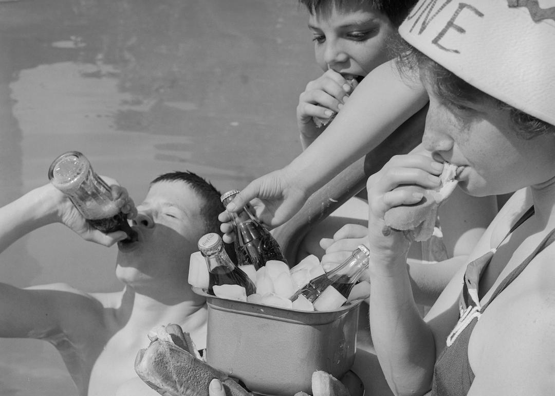 Youngsters dig into a soft drink cooler near a pool in the 1960s.