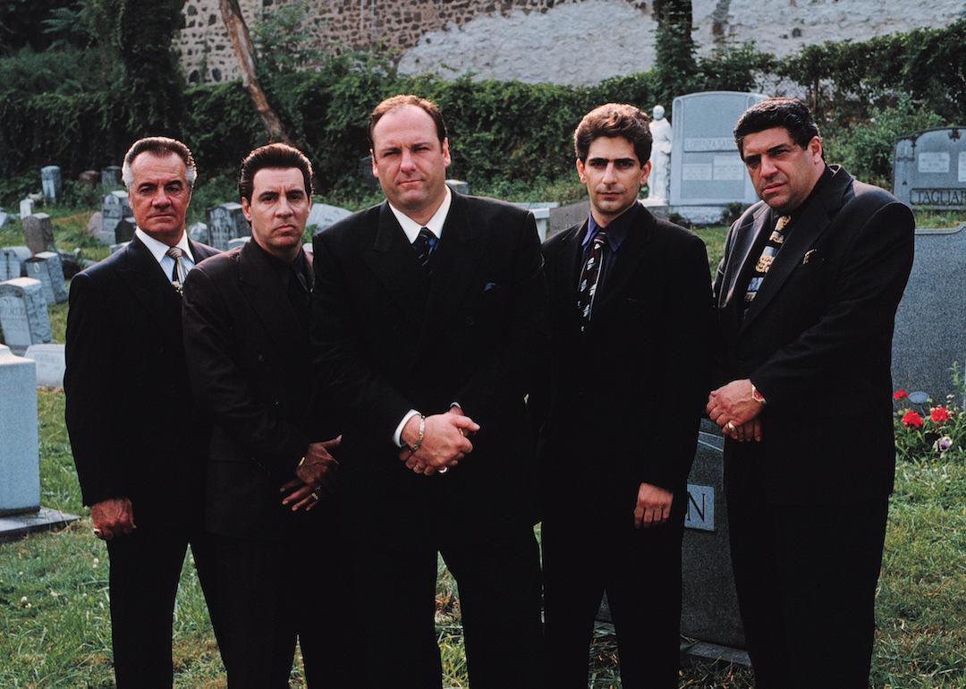 Actors Tony Sirico, Steve Van Zandt, James Gandolfini, Michael Imperioli, and Vincent Pastore wear suits and stand in a cemetery in 'The Sopranos.'