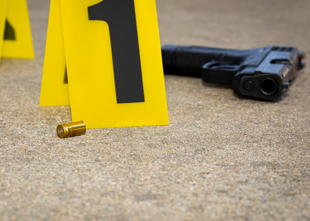 Gun shell casing and gun at crime scene, with evidence sign.