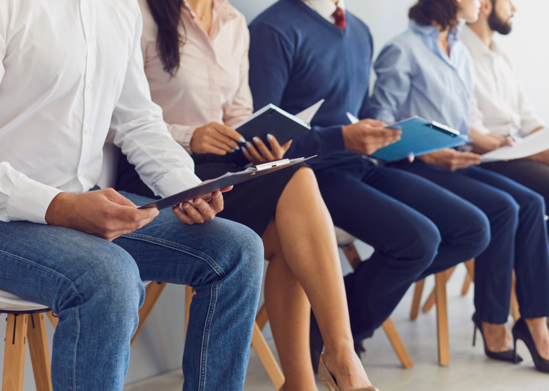 Job candidates sit in chairs as they wait to be interviewed.